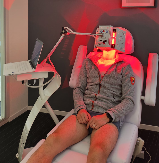 Thérapie lumière rouge avec casque, homme assis.
